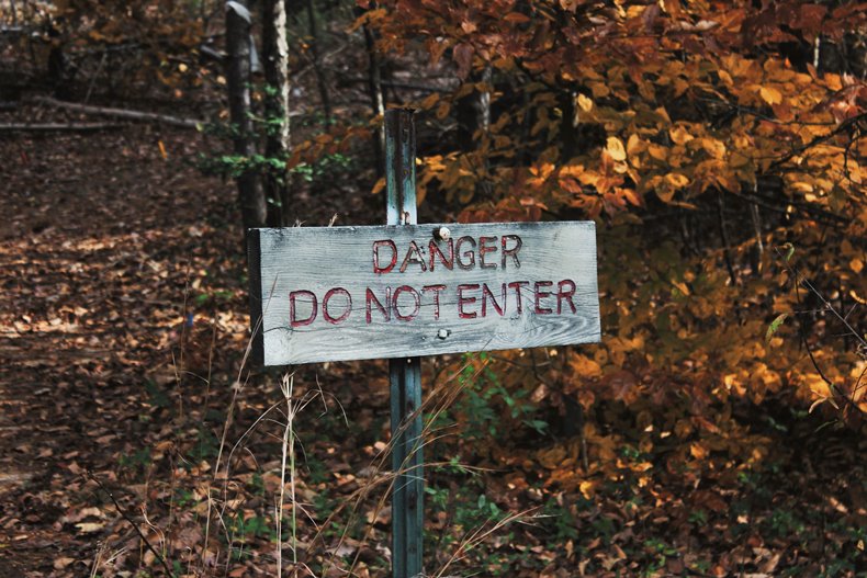 「DANGER DO NOT ENTER」と書かれた立札と山の風景