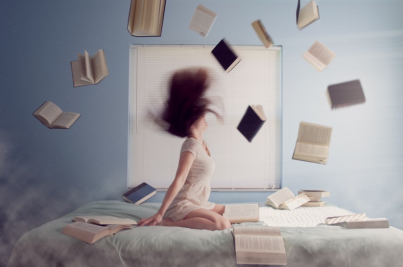 ベッドの上に座って頭を大きく振る女性と飛び散るたくさんの本